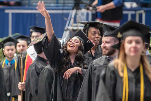 Graduate waving to audience at commencement