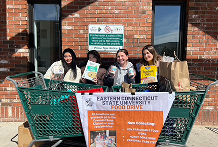 Students posing for photo behind shopping carts for food drive