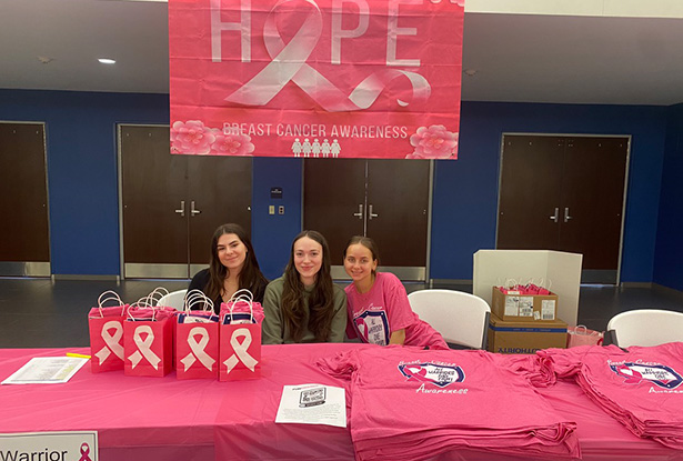 students sitting at table to promote breast cancer awareness