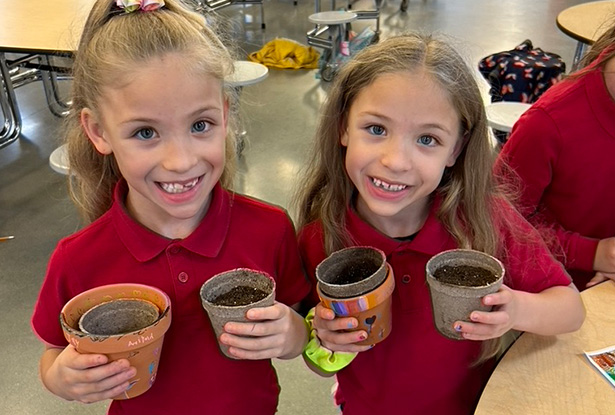 children holding small pots for planting
