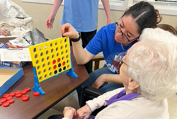 student playing Connect Four with a senior citizen