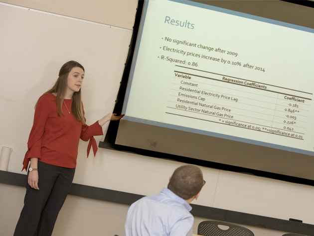 professor teaching class in front of projection screen