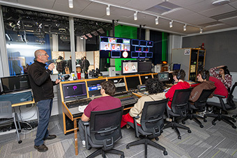 Utterback (left) assists students with production.