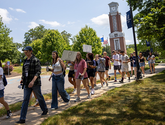 students walking around campus with the clocktower in the background