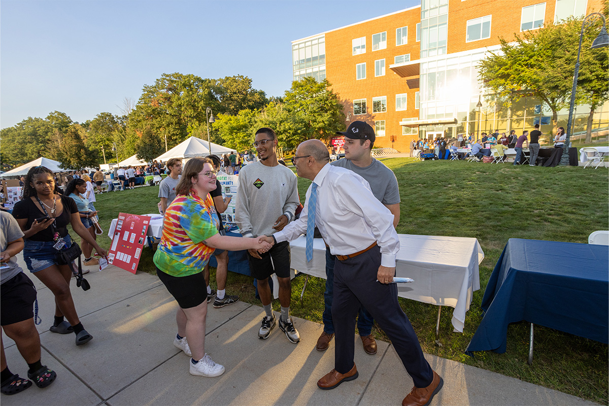 President Ismaili shaking hands with a student