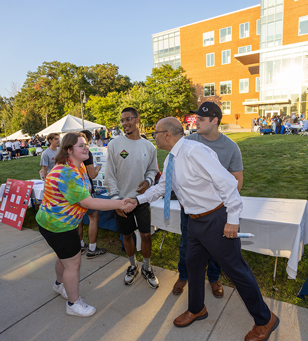 President Ismaili shaking hands with a student