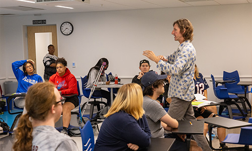 Professor walking through class talking to students